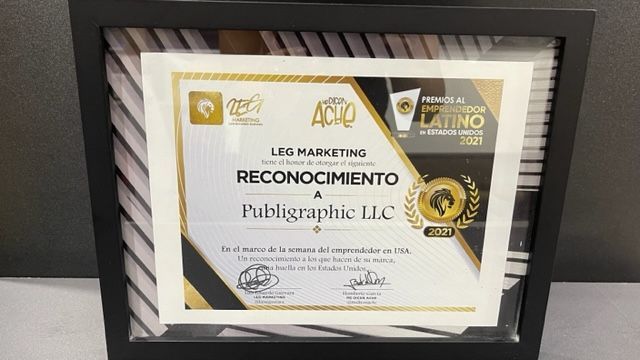 A certificate is sitting in a black frame on a table.