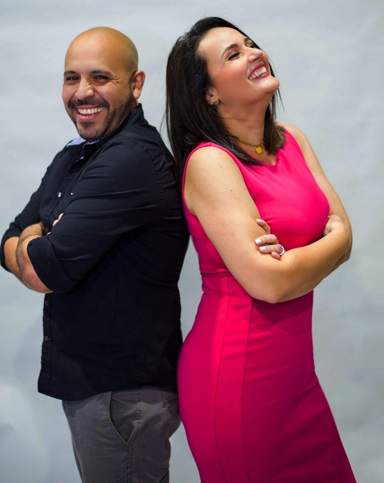 A man and a woman are standing back to back and smiling