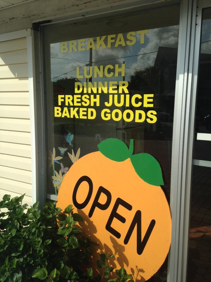 Window sign advertising breakfast, lunch, dinner, fresh juice, and baked goods. Orange 