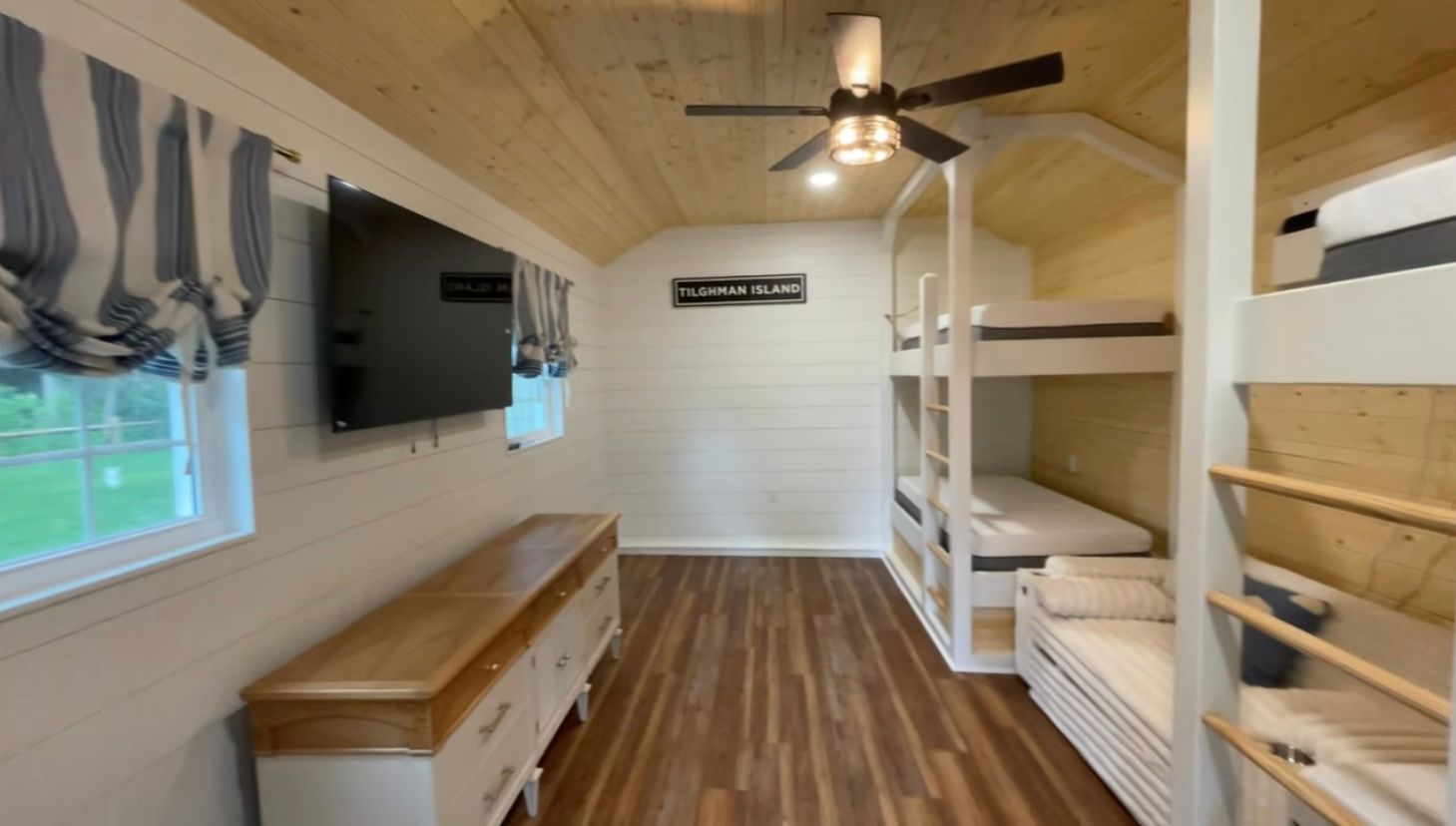 A room with bunk beds and a flat screen tv on the wall.