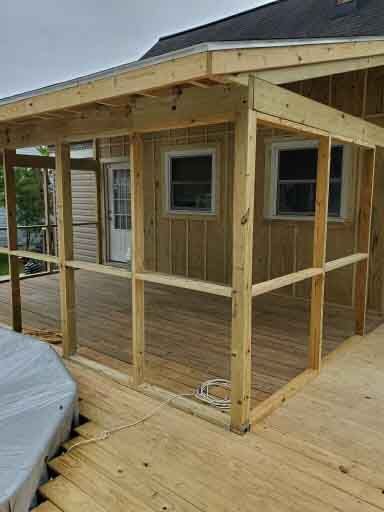 A screened in porch is being built on the side of a house.