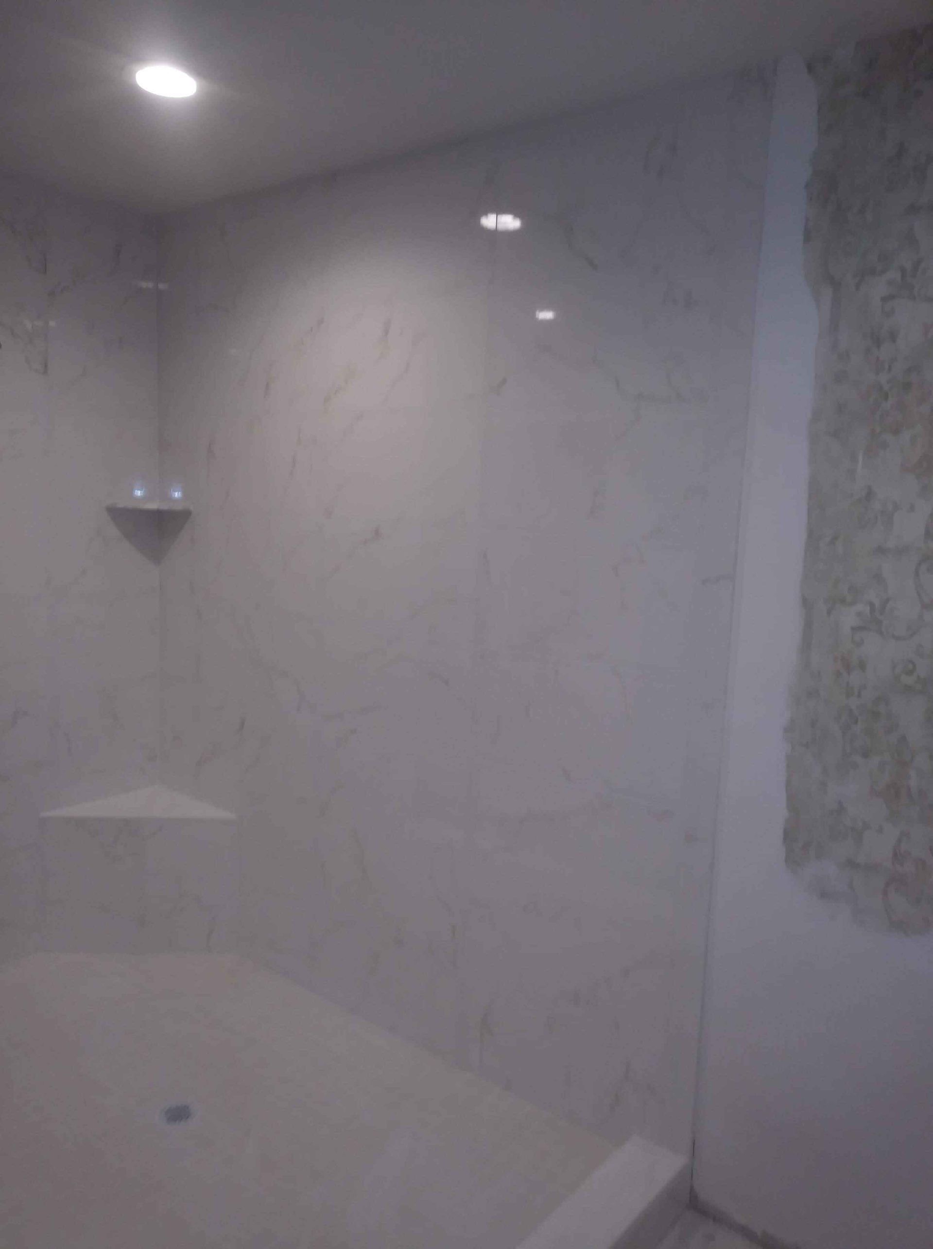 A bathroom with white tiles and a walk in shower.