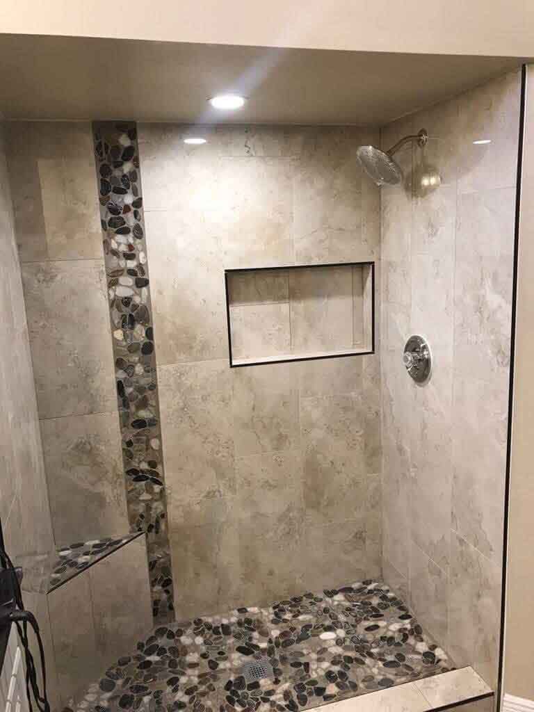 A walk in shower with a glass door and a shower head.