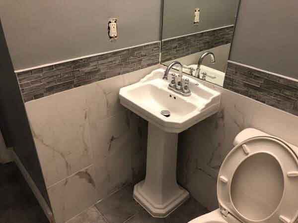 A bathroom with a toilet , sink and mirror.