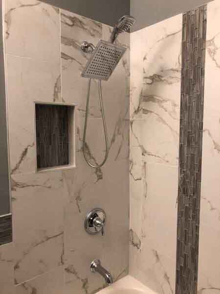 A bathroom with marble tiles and a shower head.