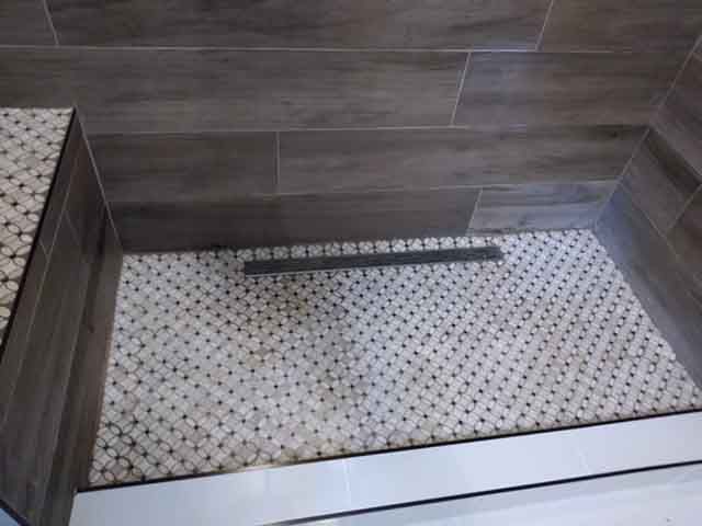 A shower stall with a tiled floor and a drain.