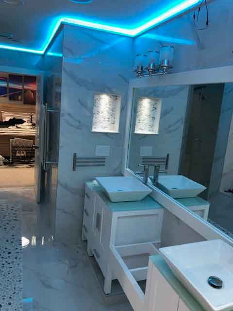 A bathroom with two sinks , a mirror , and blue lights.