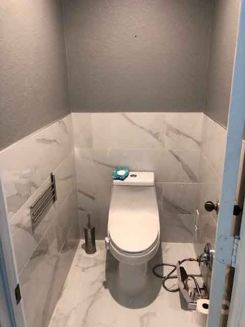 A toilet is sitting in a small bathroom next to a door.