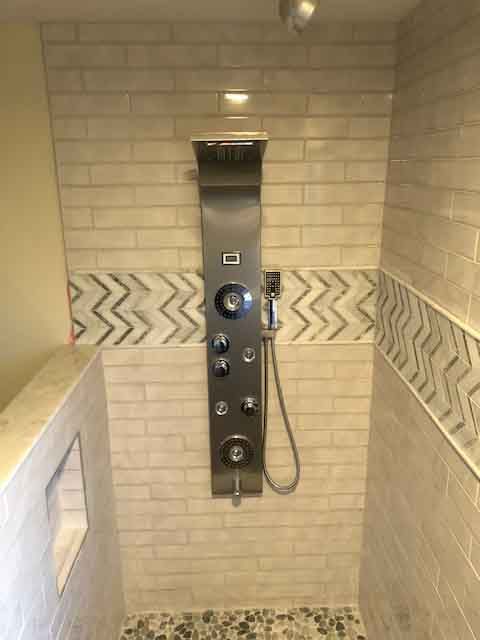 A shower with a stainless steel shower head in a bathroom.
