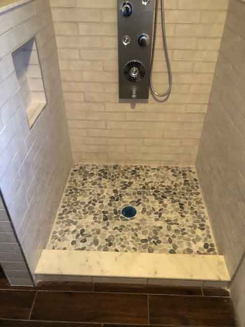 A shower with a tiled floor and a shower head.