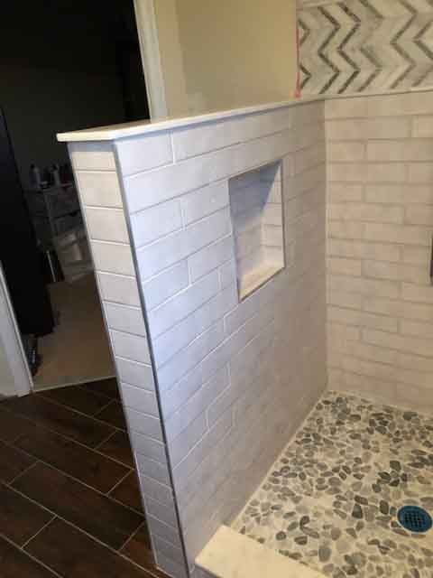 A bathroom with a walk in shower and a tiled wall.