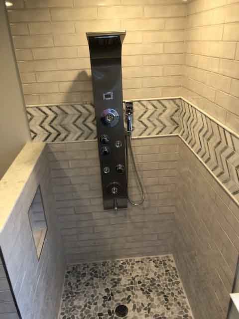 A bathroom with a walk in shower and a stainless steel shower head.