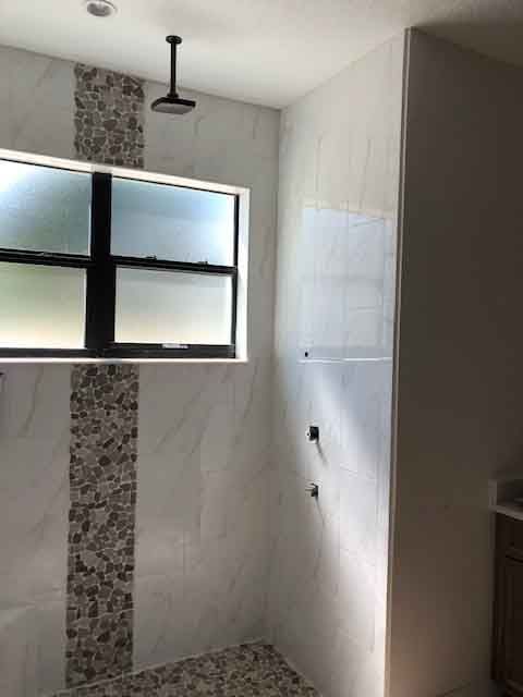 A bathroom with a walk in shower and a window.