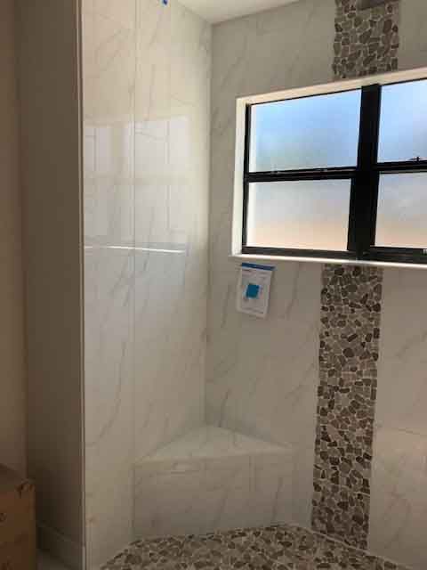 A bathroom with a walk in shower and a window.