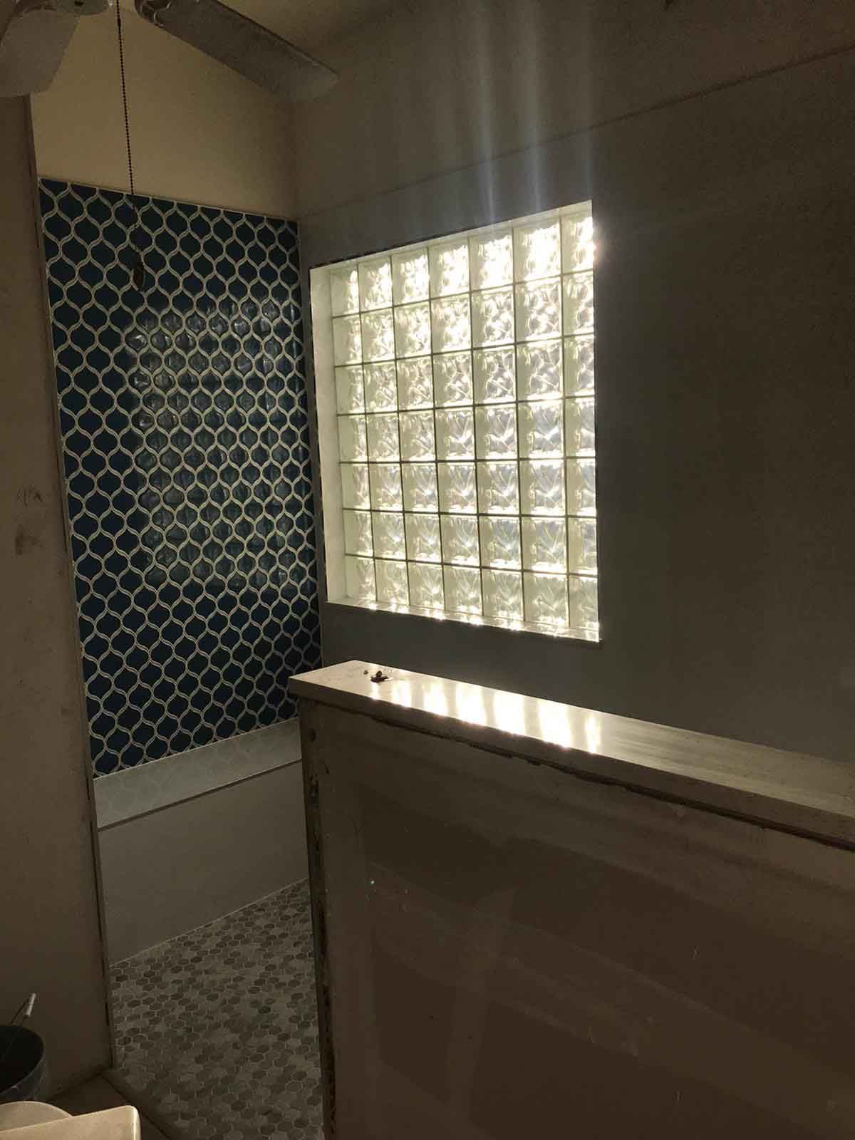 A bathroom with a bathtub and a glass block window.