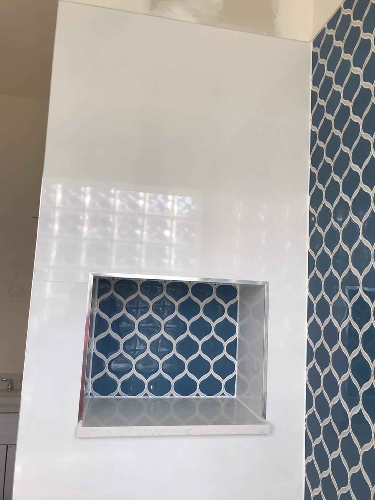 A bathroom with blue and white tiles and a niche in the wall.