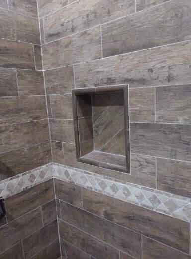 A bathroom with wooden tiles and a stainless steel shower niche.