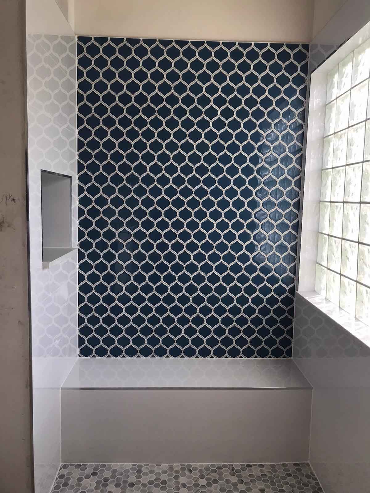 A shower with a blue and white tile wall and a window.