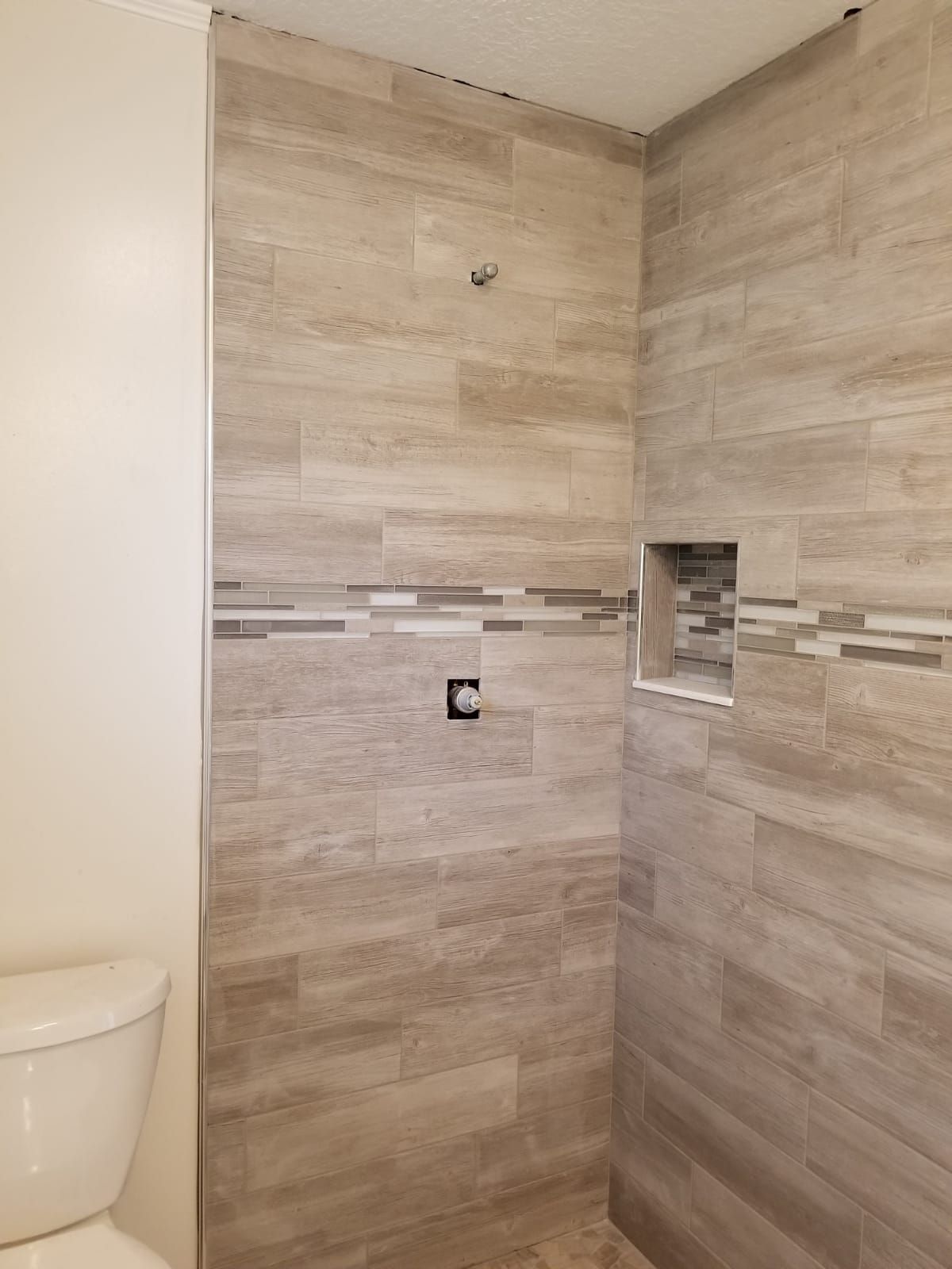 A bathroom with a toilet , shower , and tiled walls.