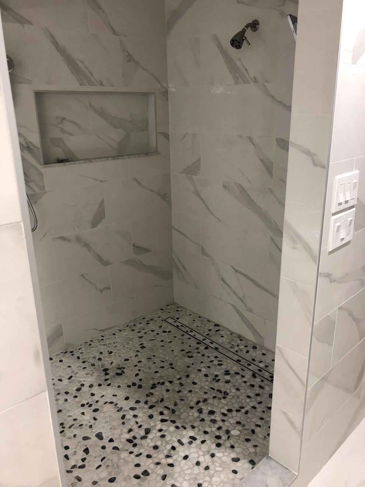 A bathroom with a walk in shower and a shower head.