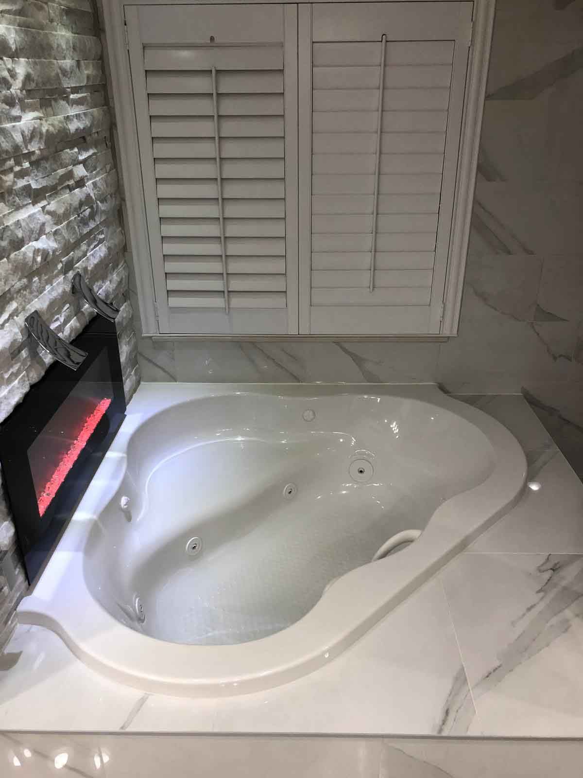 A jacuzzi tub in a bathroom next to a fireplace.