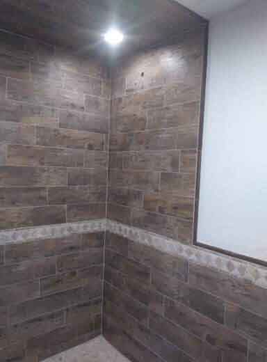 A bathroom with wooden tiles on the walls and a window.