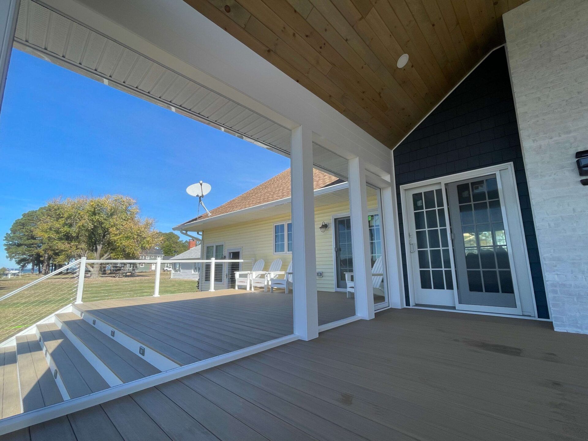 A large porch with a sliding glass door leading to a house.