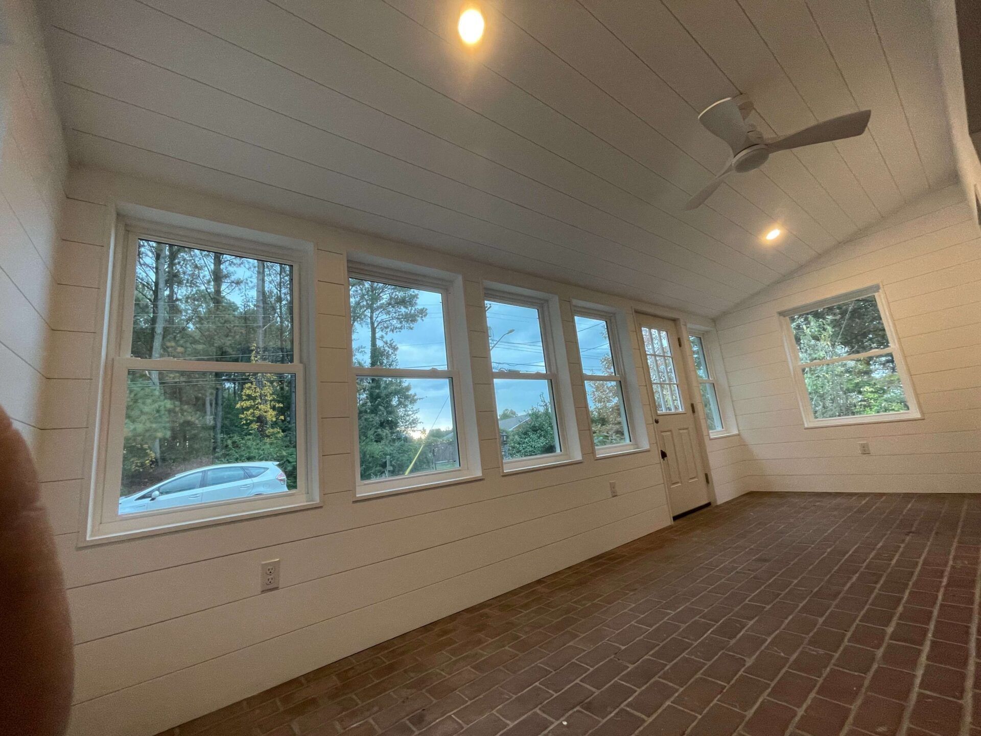 A room with a lot of windows and a ceiling fan.