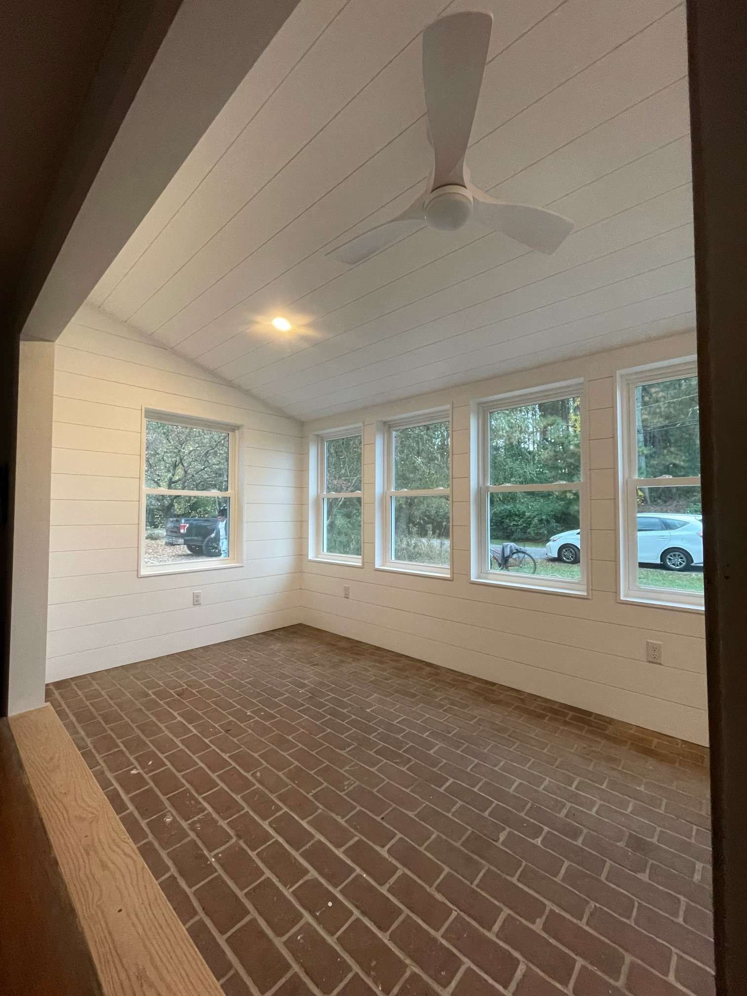 An empty room with a ceiling fan and lots of windows.