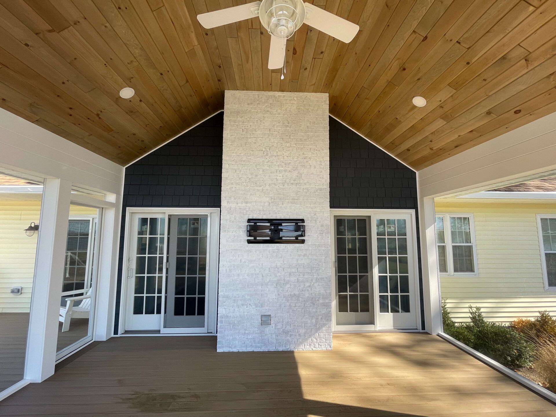 A porch with a fireplace and a ceiling fan