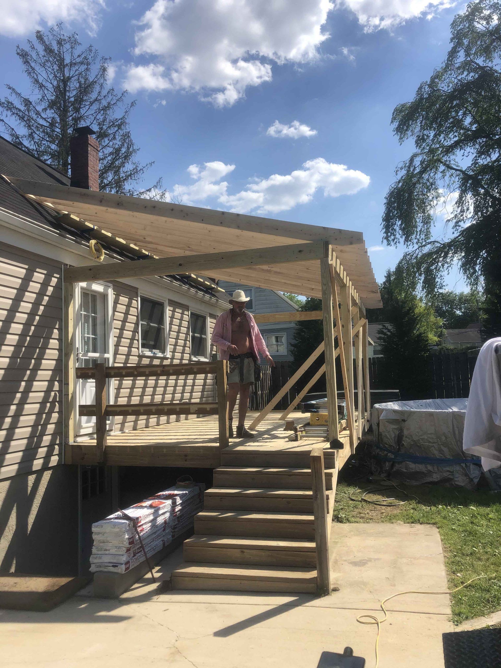 A man is standing on a wooden deck in front of a house.