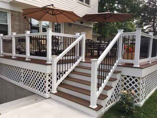 There are two umbrellas on the deck of a house.