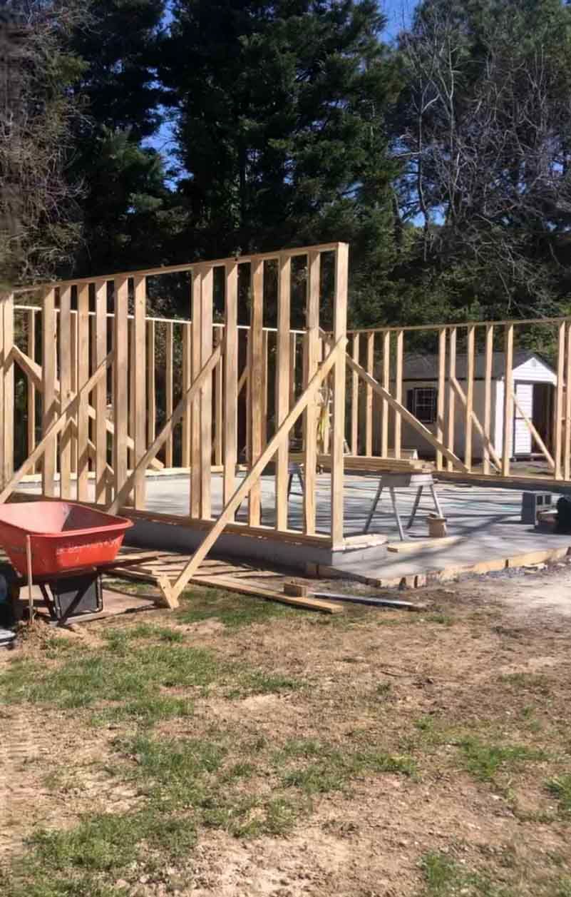 A wheelbarrow is parked in front of a house under construction.