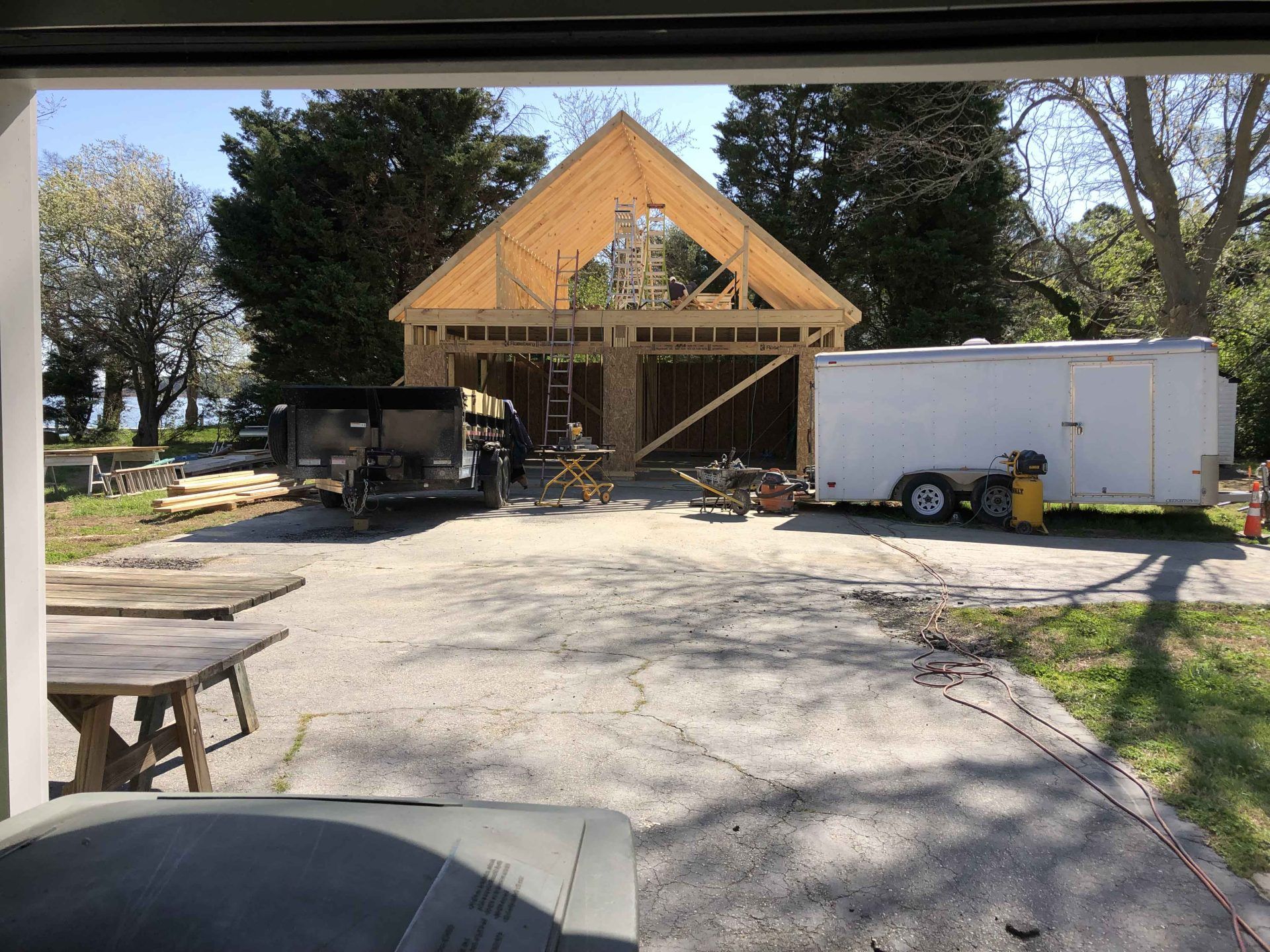 A white trailer is parked in front of a house under construction.