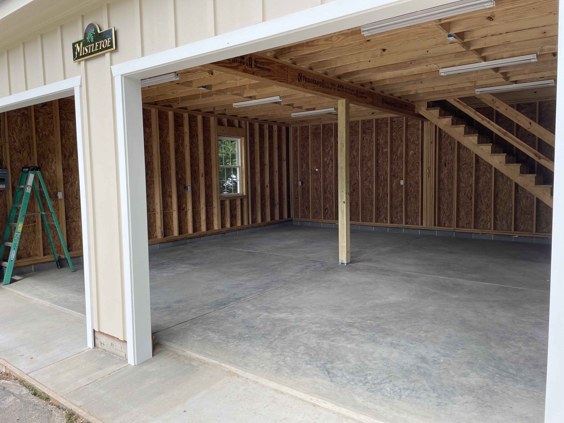 A garage under construction with stairs going up to the second floor.