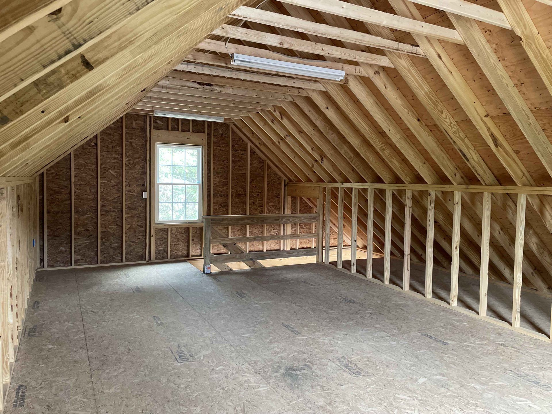 An empty attic with wooden beams and a window.