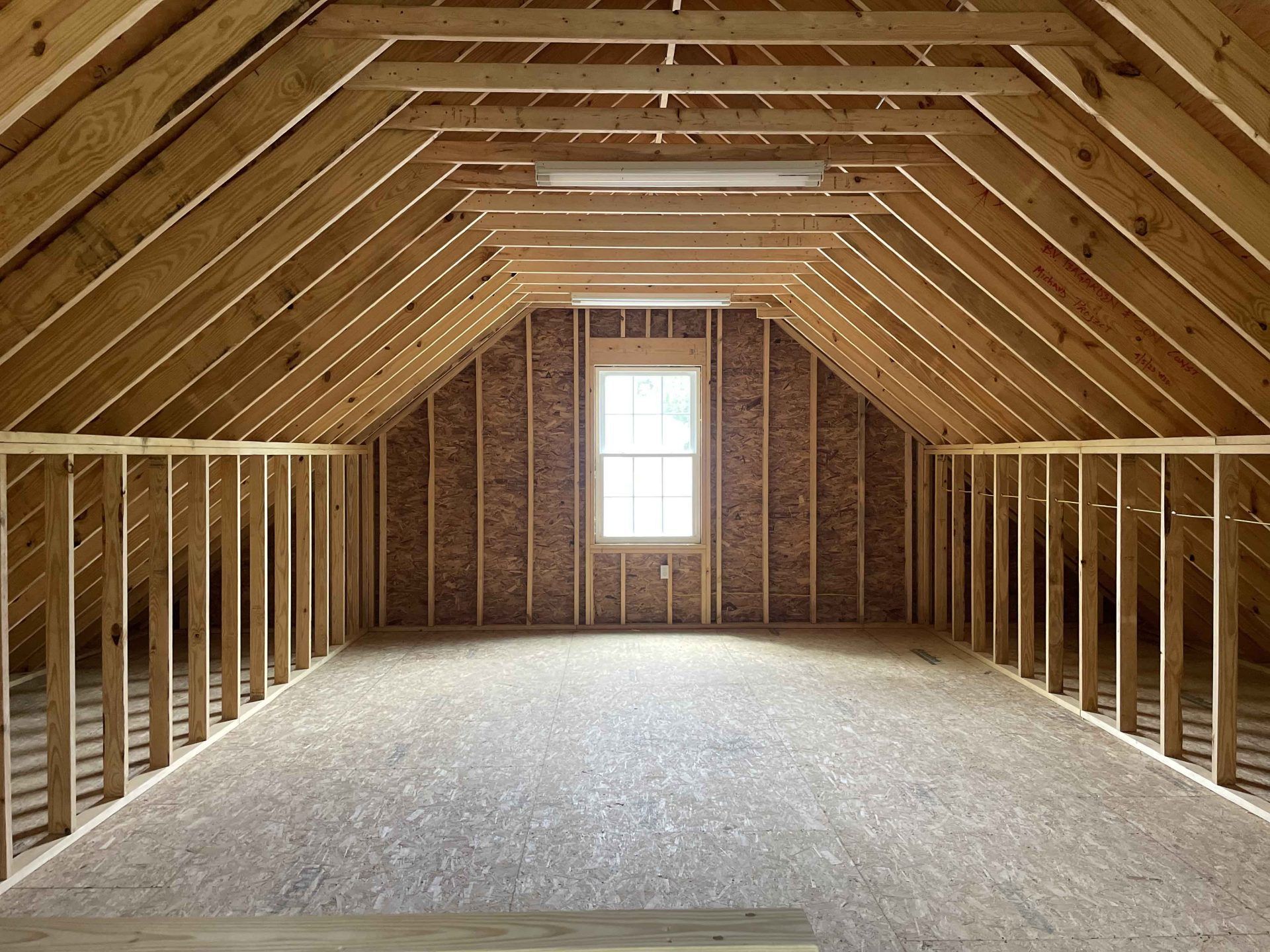 An empty attic with wooden beams and a window