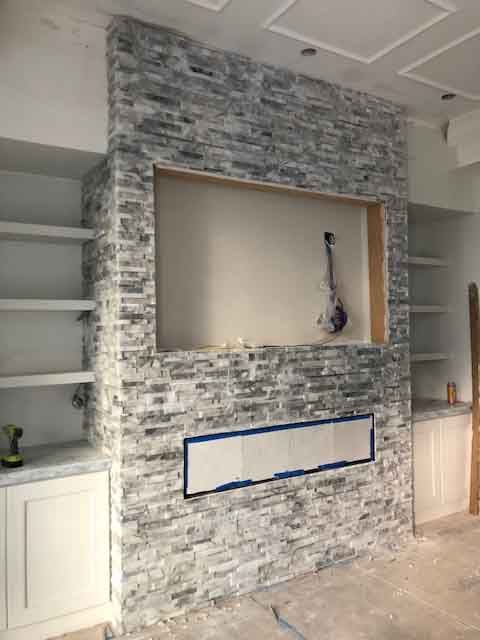 A living room with a brick fireplace and shelves.