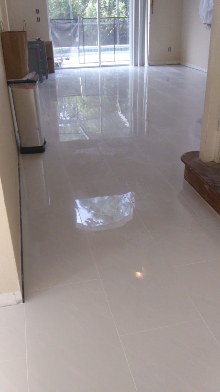 A living room with a white tile floor and a sliding glass door.