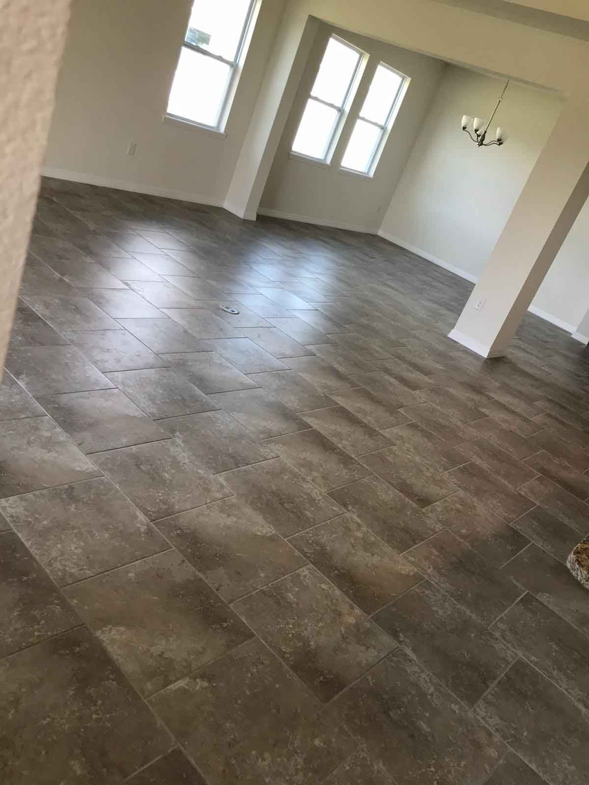 A large empty room with a tiled floor and a chandelier.
