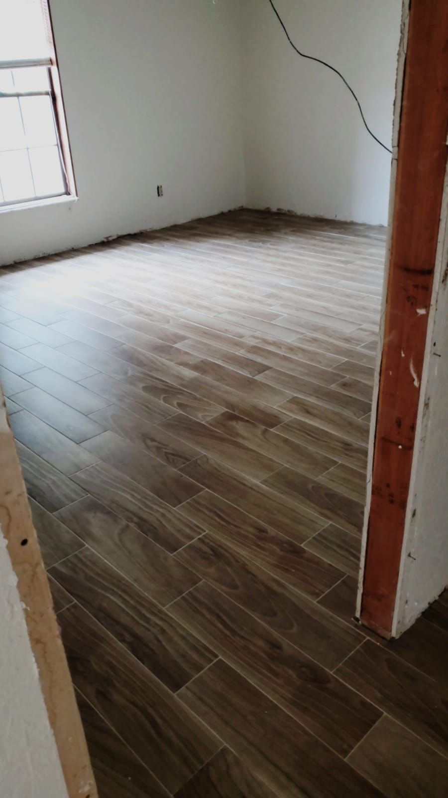 A room with a wooden floor and a window.
