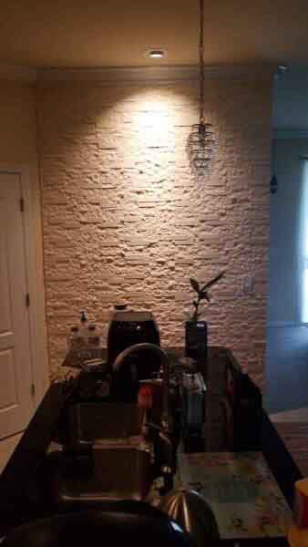 A kitchen with a brick wall and a black counter top.