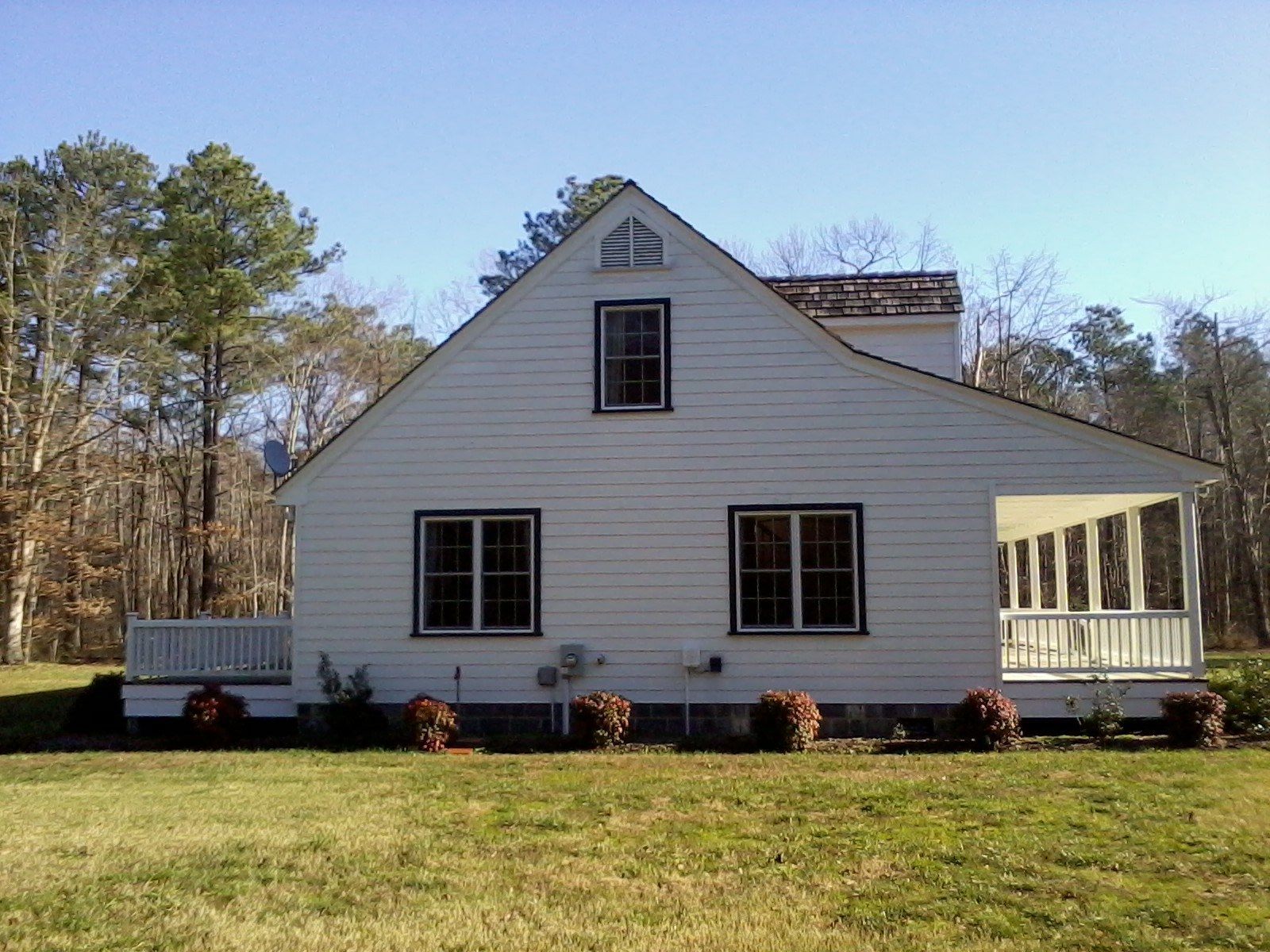 A white house with a porch and trees in the background