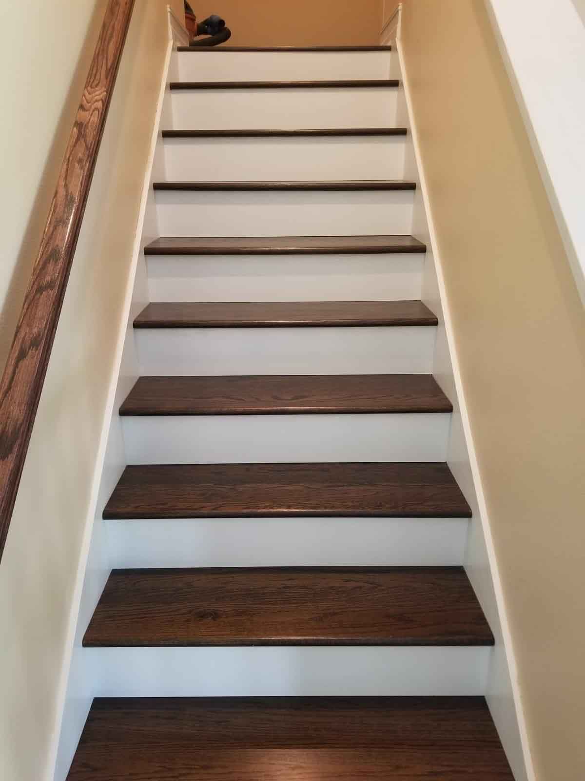 A set of stairs with wooden steps and white railing.
