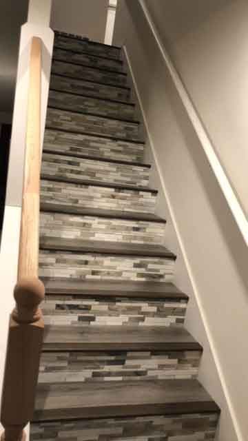 A staircase with a wooden railing and tiled steps in a house.