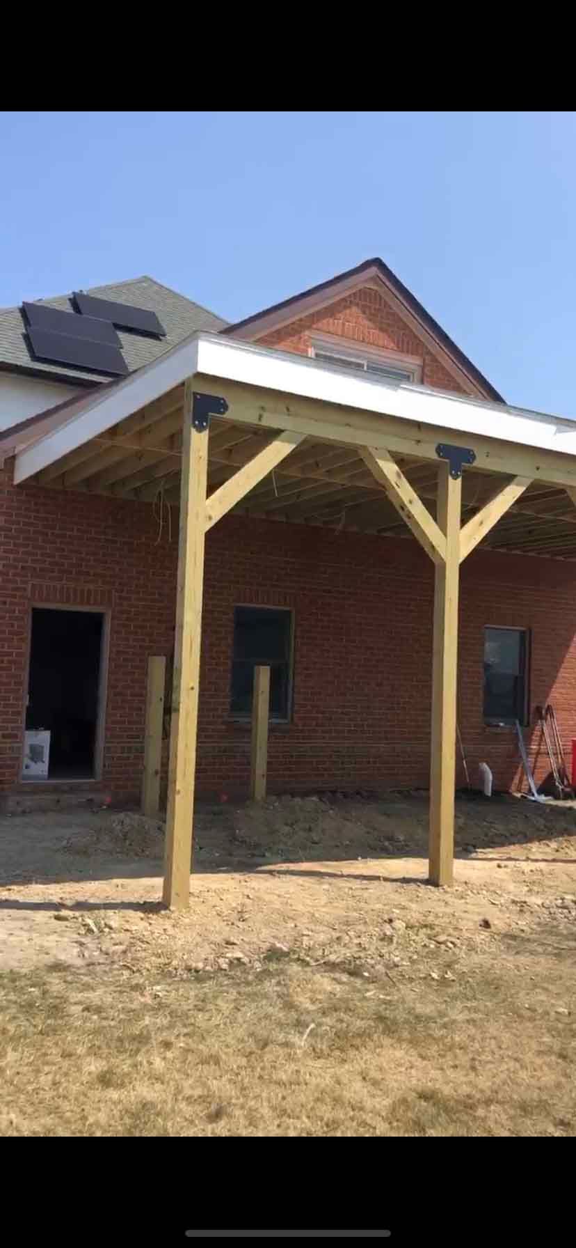 A wooden porch is being built in front of a brick house.