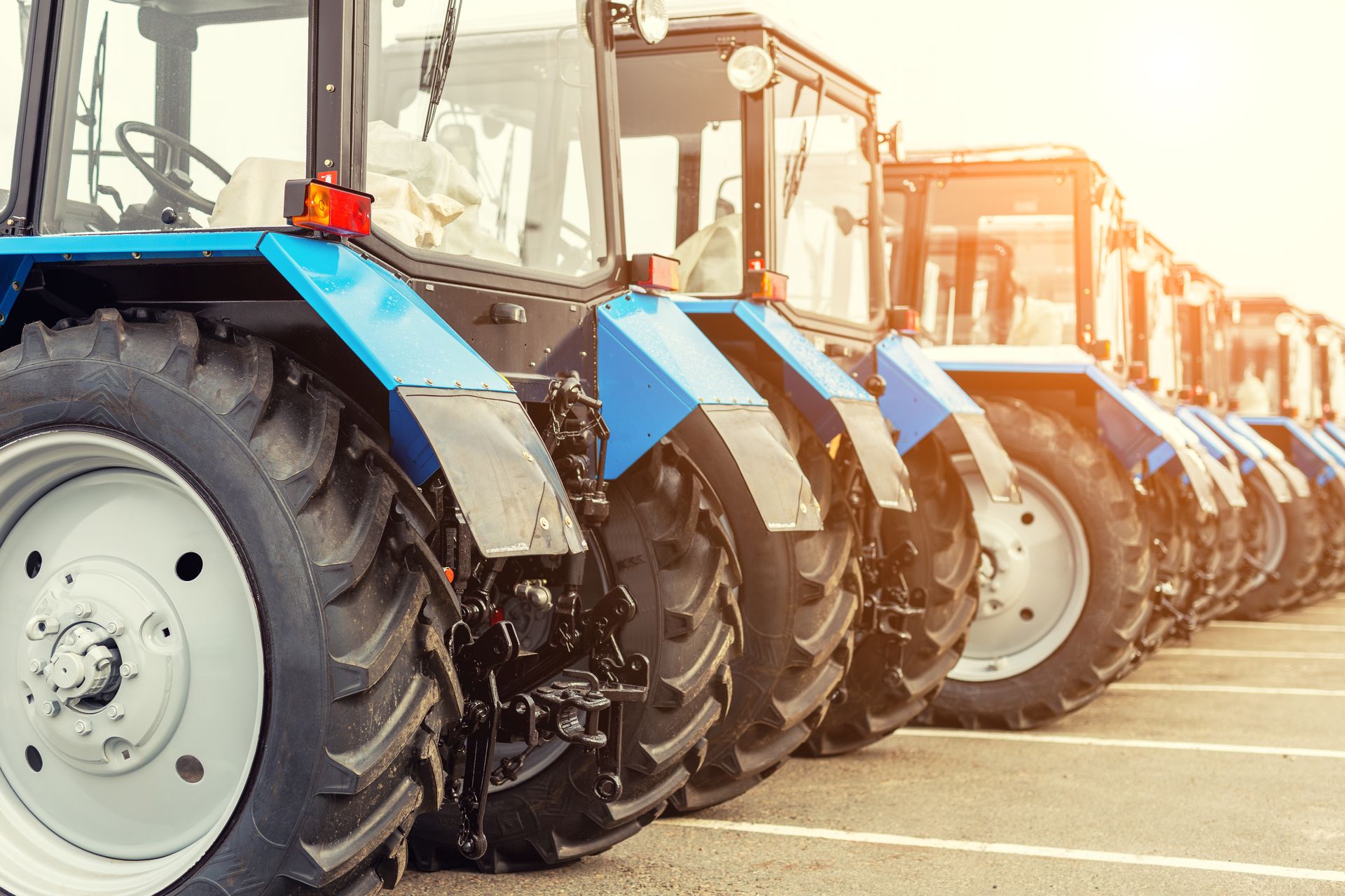 Blue tractors lined up outdoors.