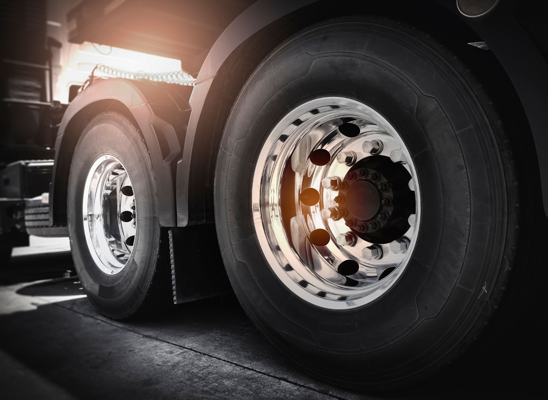 Close-up of two large truck tires with shiny rims.
