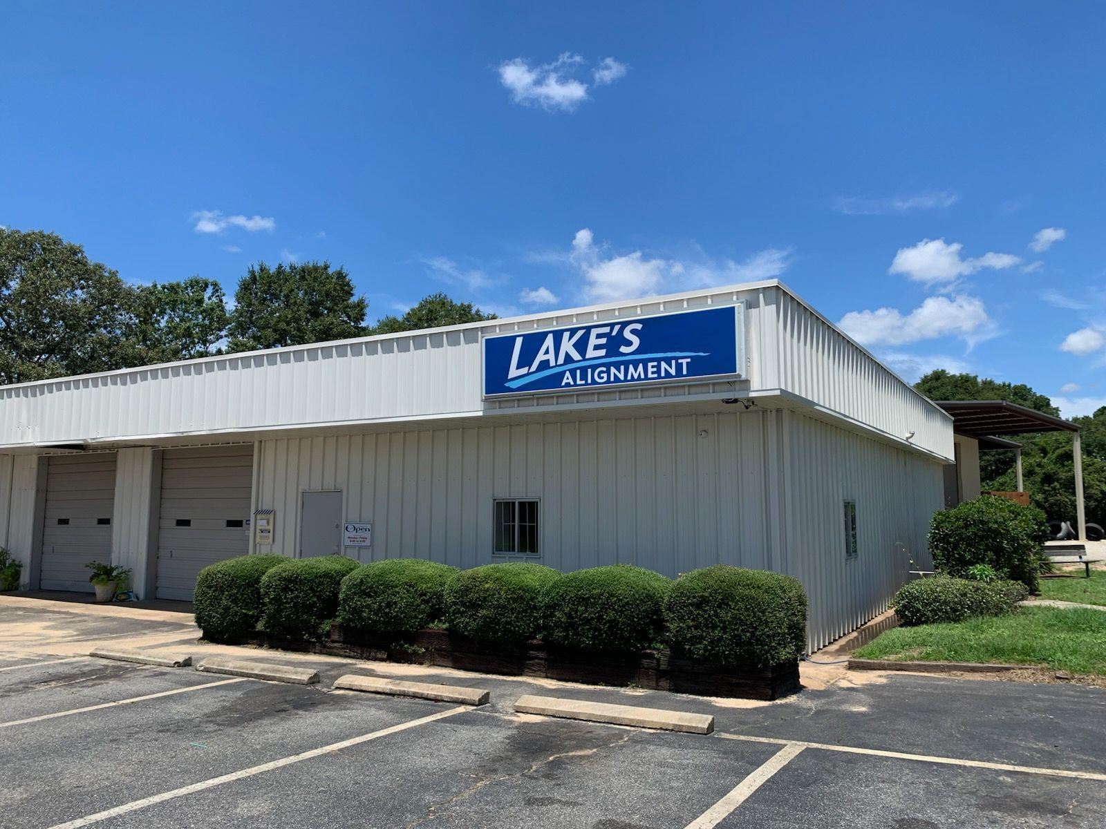 Lake's Alignment auto shop with white exterior, blue sign, overcast sky.