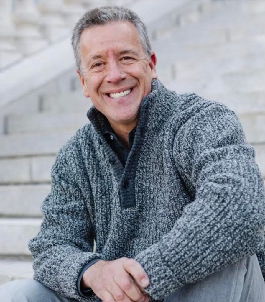 A woman in a cowboy hat is standing next to a brown horse.